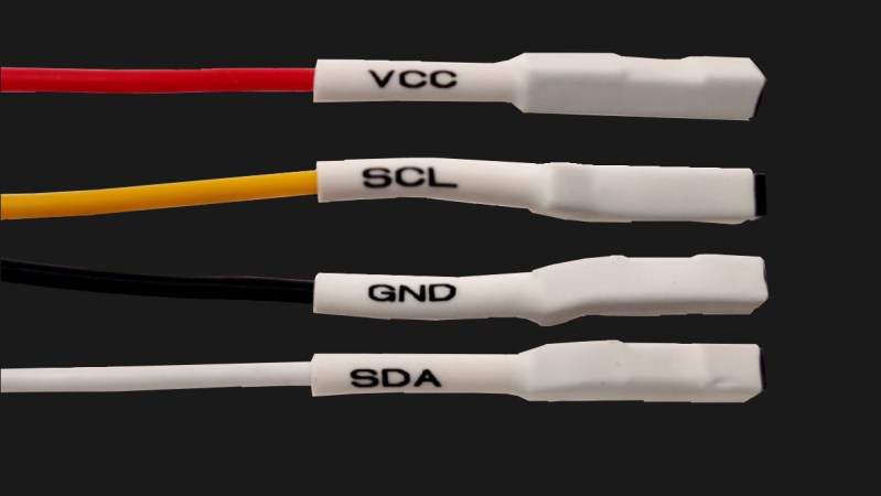 Four jumper wires with white heatshrink on them, labelled VCC, SCL, SDA and GND